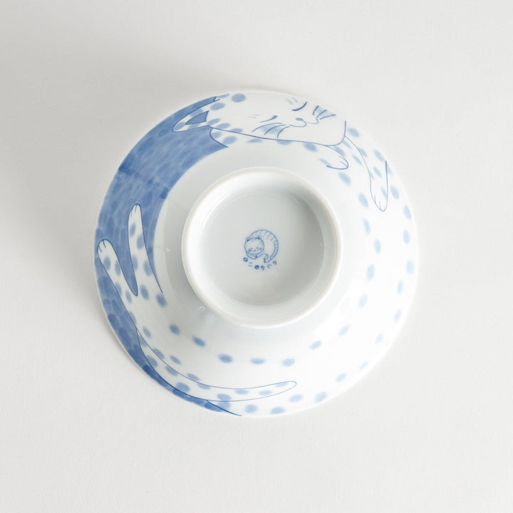 A ramen bowl with a design of a blue and white spotted cat, appearing cozy and content.