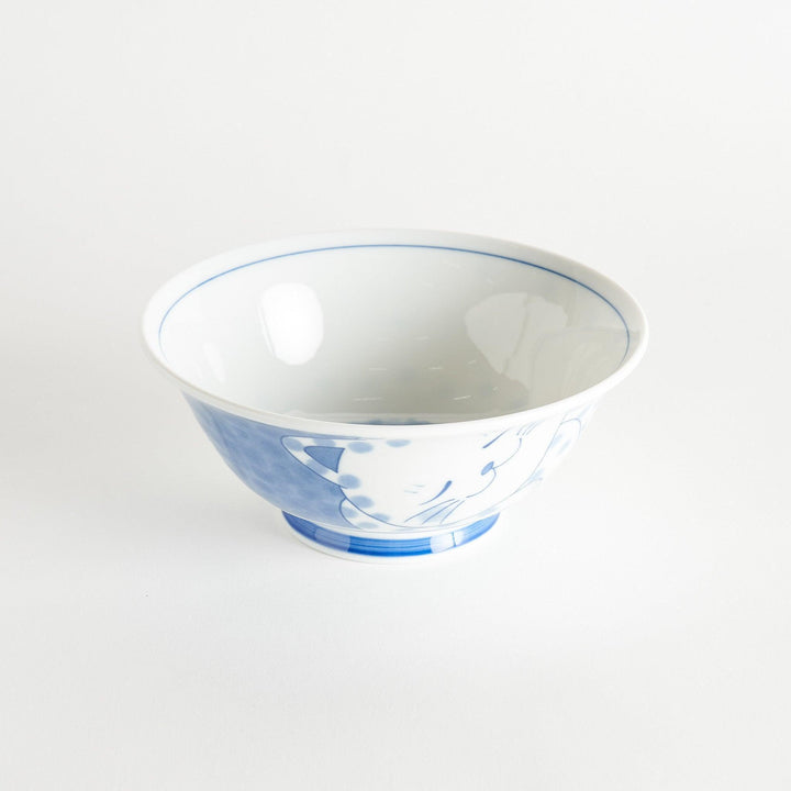 A ramen bowl with a design of a blue and white spotted cat, appearing cozy and content.