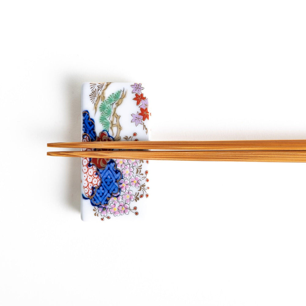 A ceramic chopstick rest shaped like a rectangular block, decorated with traditional Japanese patterns in blue, red, and green.