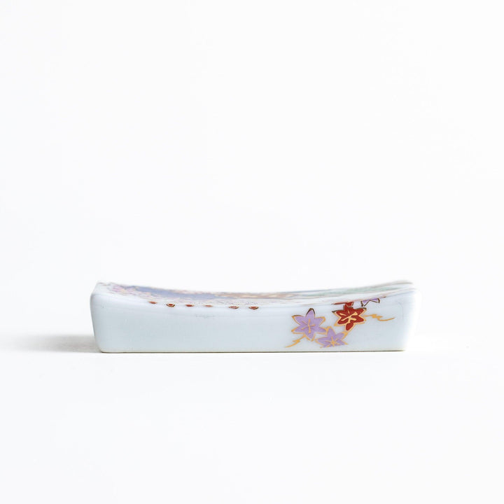 A ceramic chopstick rest shaped like a rectangular block, decorated with traditional Japanese patterns in blue, red, and green.