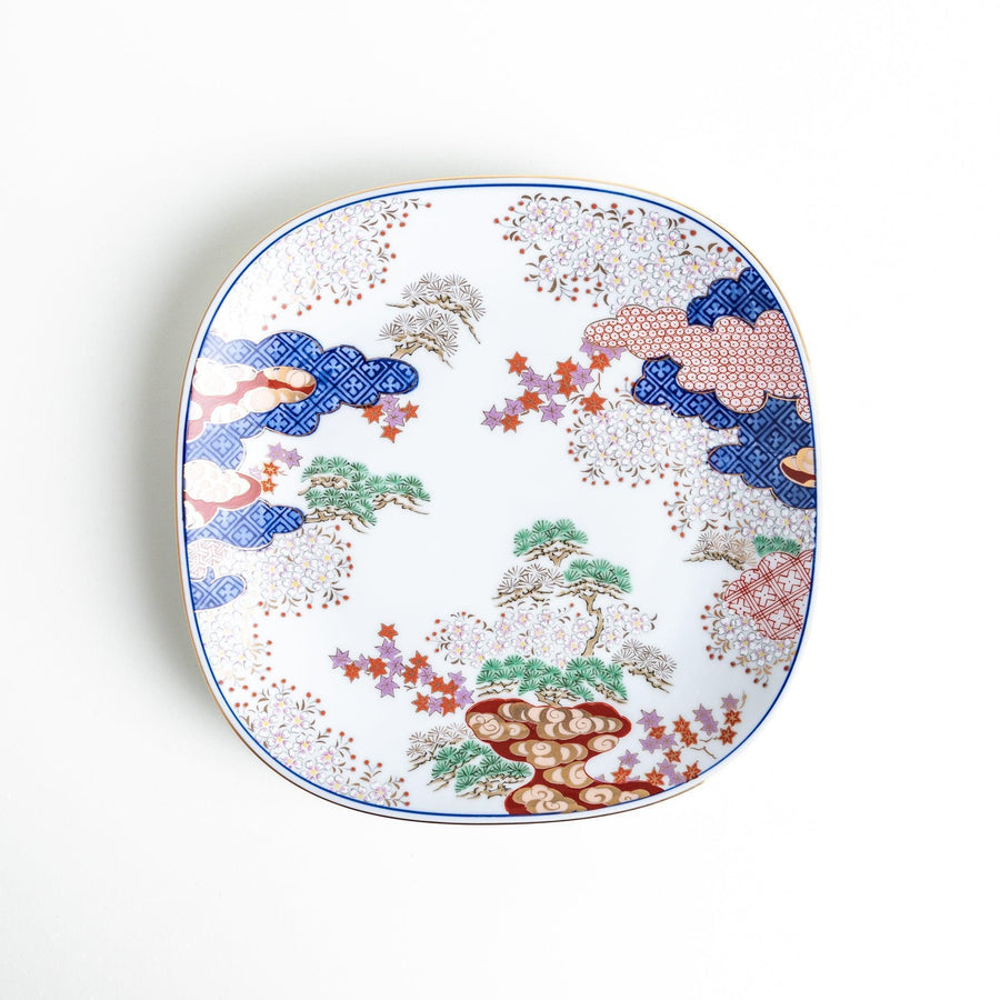 A square salad plate featuring a traditional Japanese landscape with trees, clouds, and maple leaves, framed by intricate blue and red patterns.