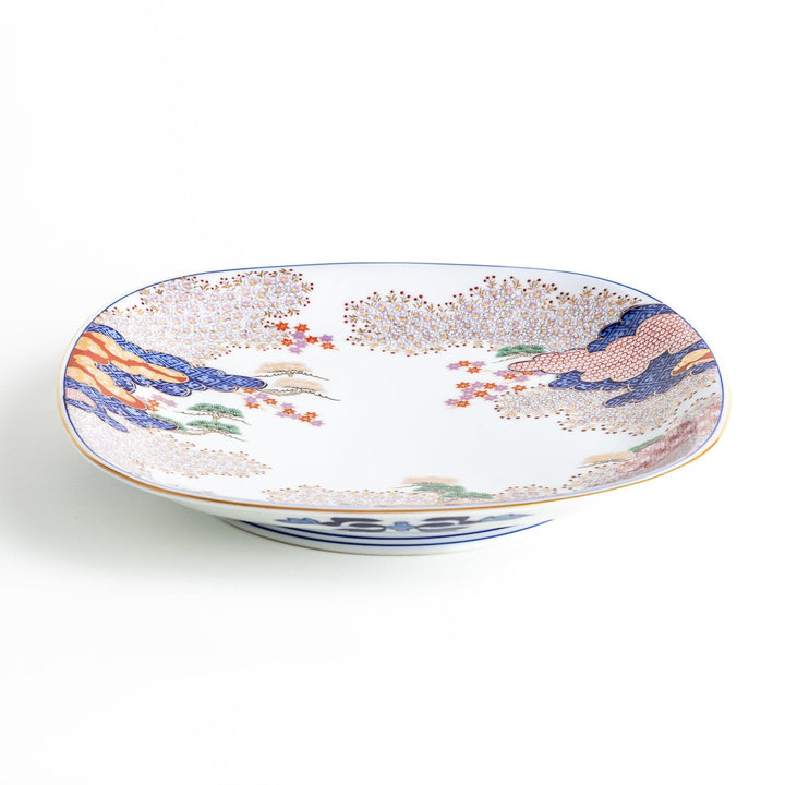 A square serving plate with a white background, decorated with a traditional Japanese landscape of trees, clouds, and red maple leaves.