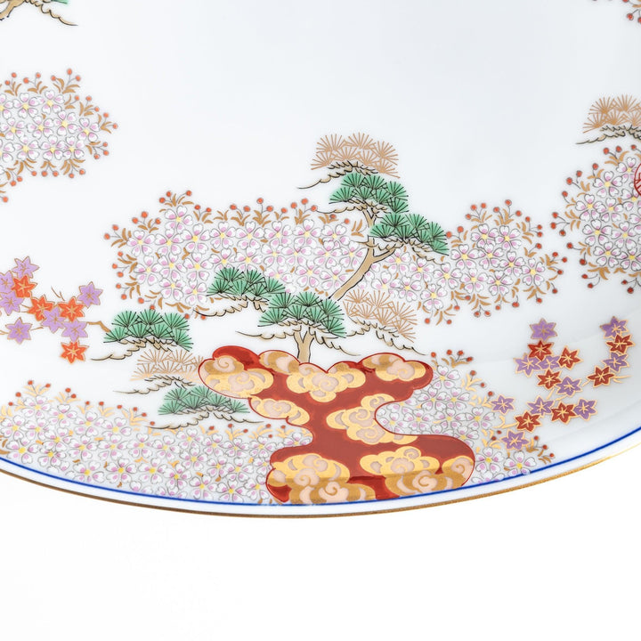 A square serving plate with a white background, decorated with a traditional Japanese landscape of trees, clouds, and red maple leaves.