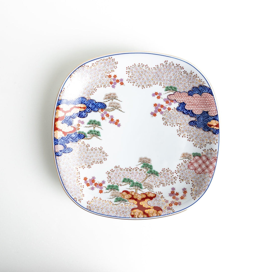 A square serving plate with a white background, decorated with a traditional Japanese landscape of trees, clouds, and red maple leaves.