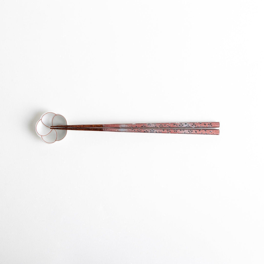 A pair of wooden chopsticks with a faded white gradient and delicate flower patterns near the top.