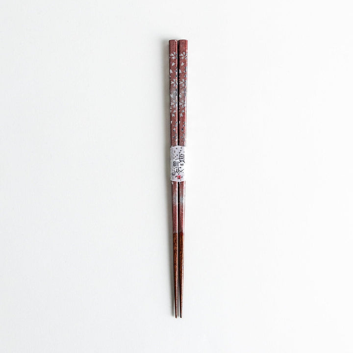 A pair of wooden chopsticks with a faded white gradient and delicate flower patterns near the top.