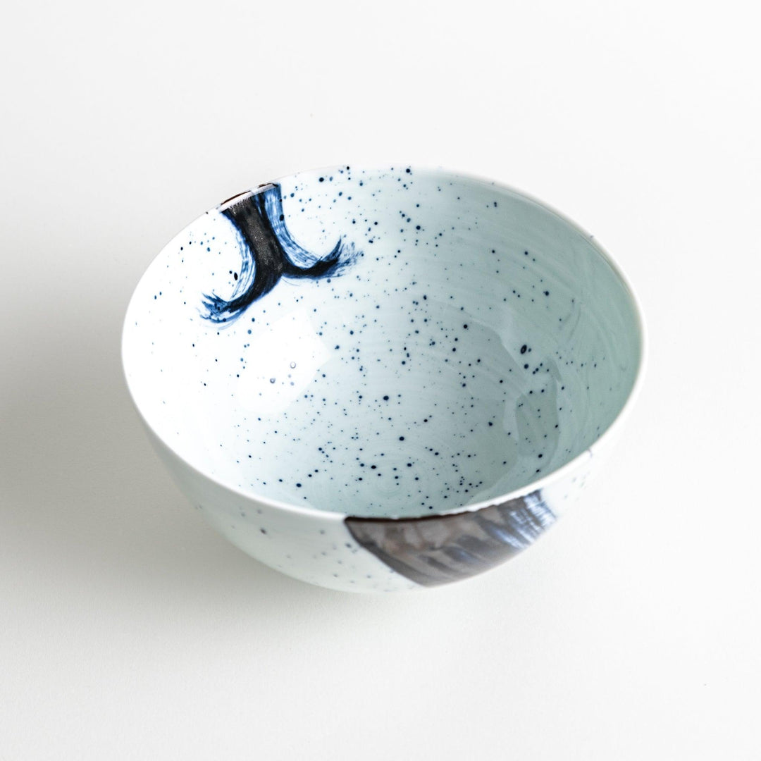 A white ceramic bowl with a striking blue brush stroke pattern.