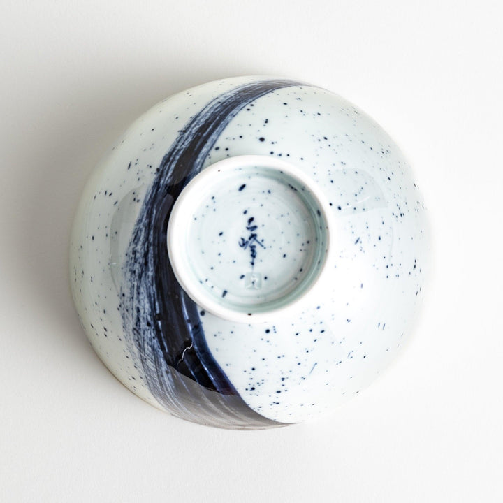 A white ceramic bowl with a striking blue brush stroke pattern.