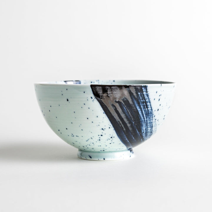 A white ceramic bowl with a striking blue brush stroke pattern.