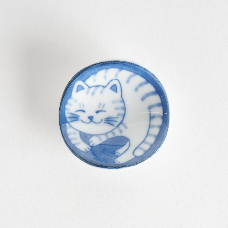 A small chopstick rest featuring a smiling blue-striped cat, curled up in a cozy position.