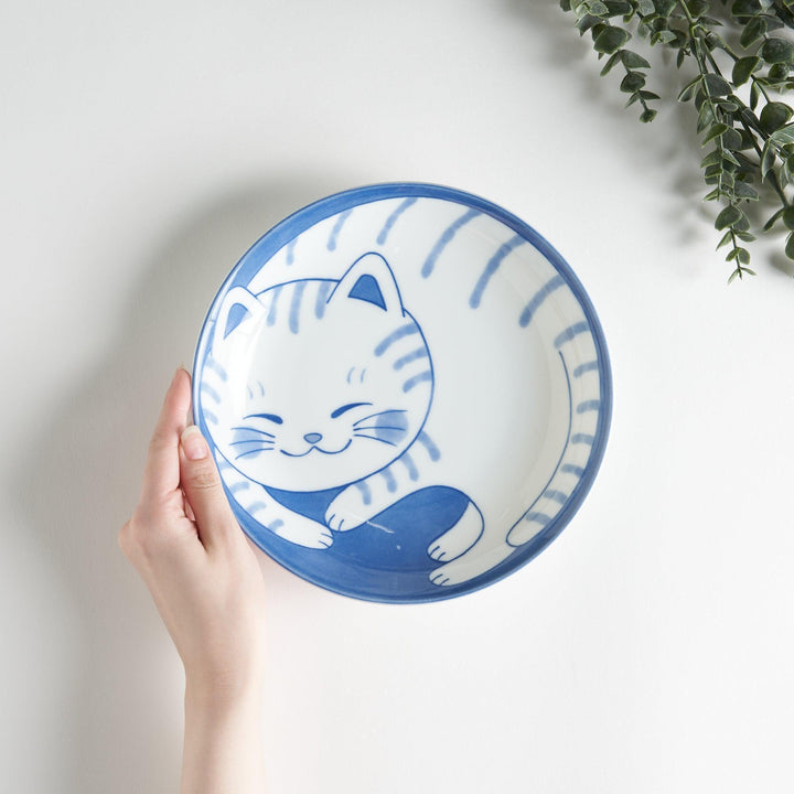 A salad plate with a blue-striped white cat, smiling with closed eyes.