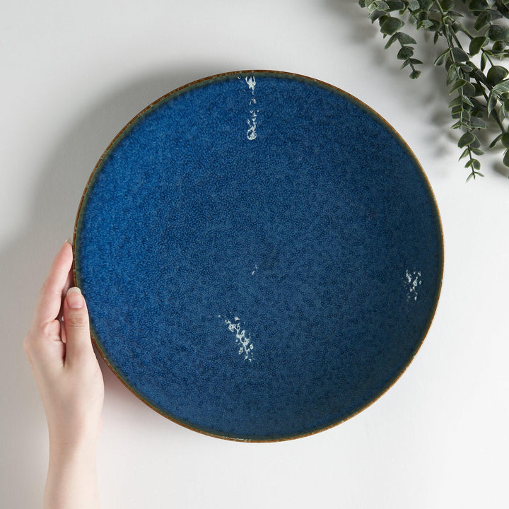 A round dinner plate with a deep blue gradient finish and a subtle textured surface.