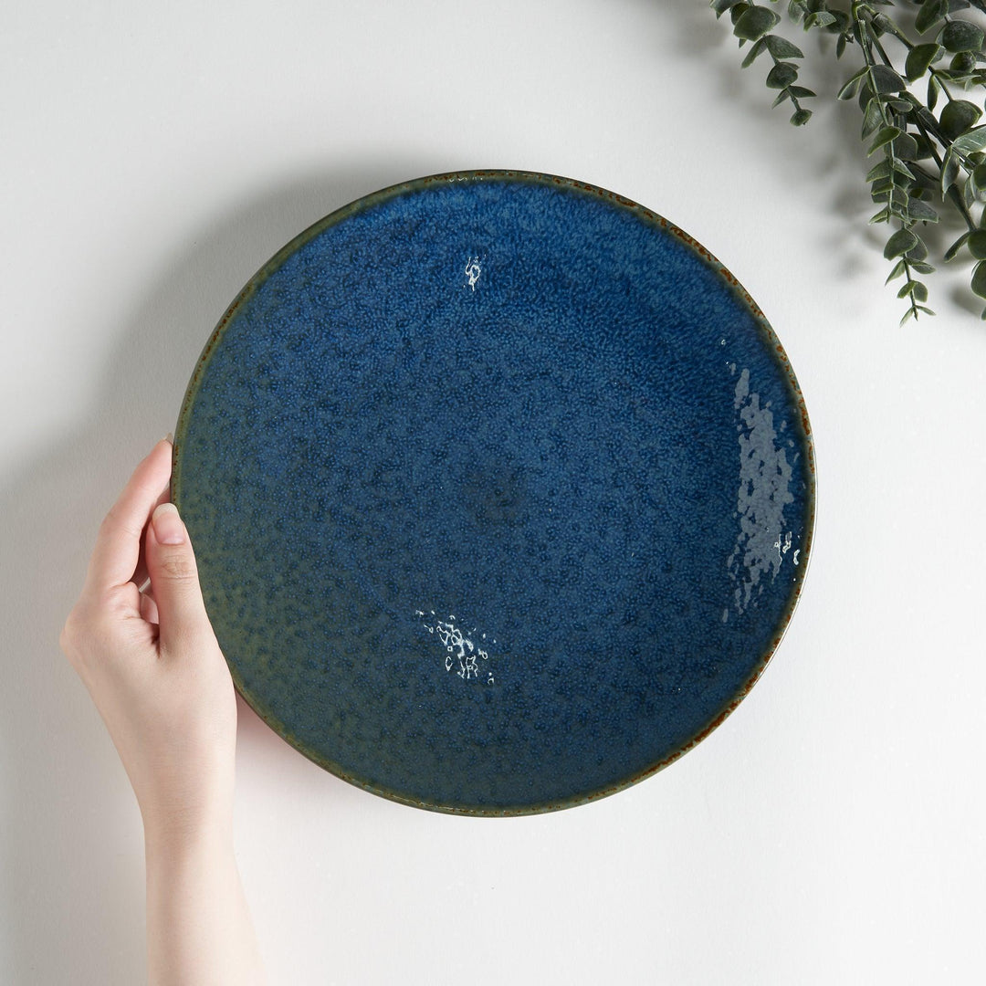 A round salad plate featuring a deep blue color and a fine speckled texture.