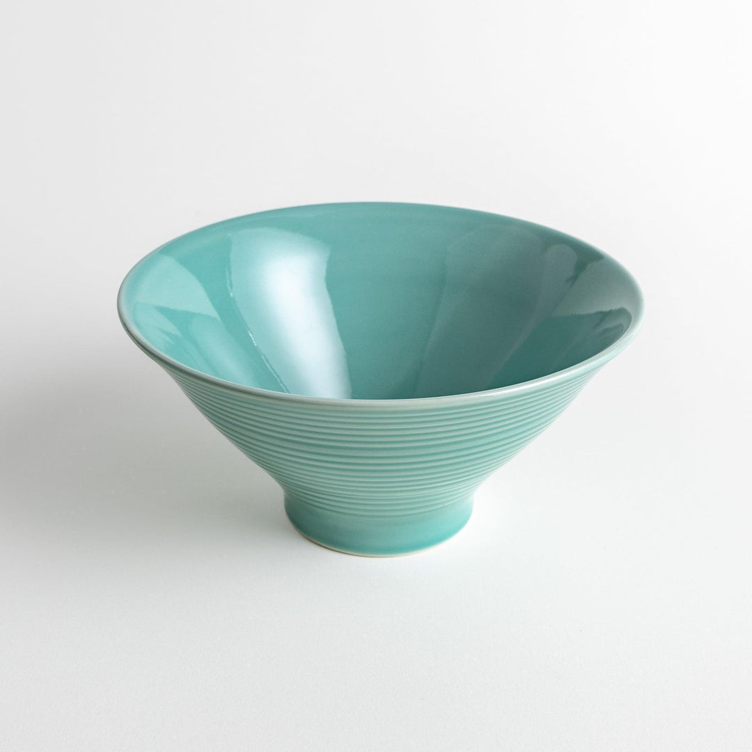 A wide, shallow porcelain bowl with a soft, matte turquoise glaze and subtle horizontal ridges.