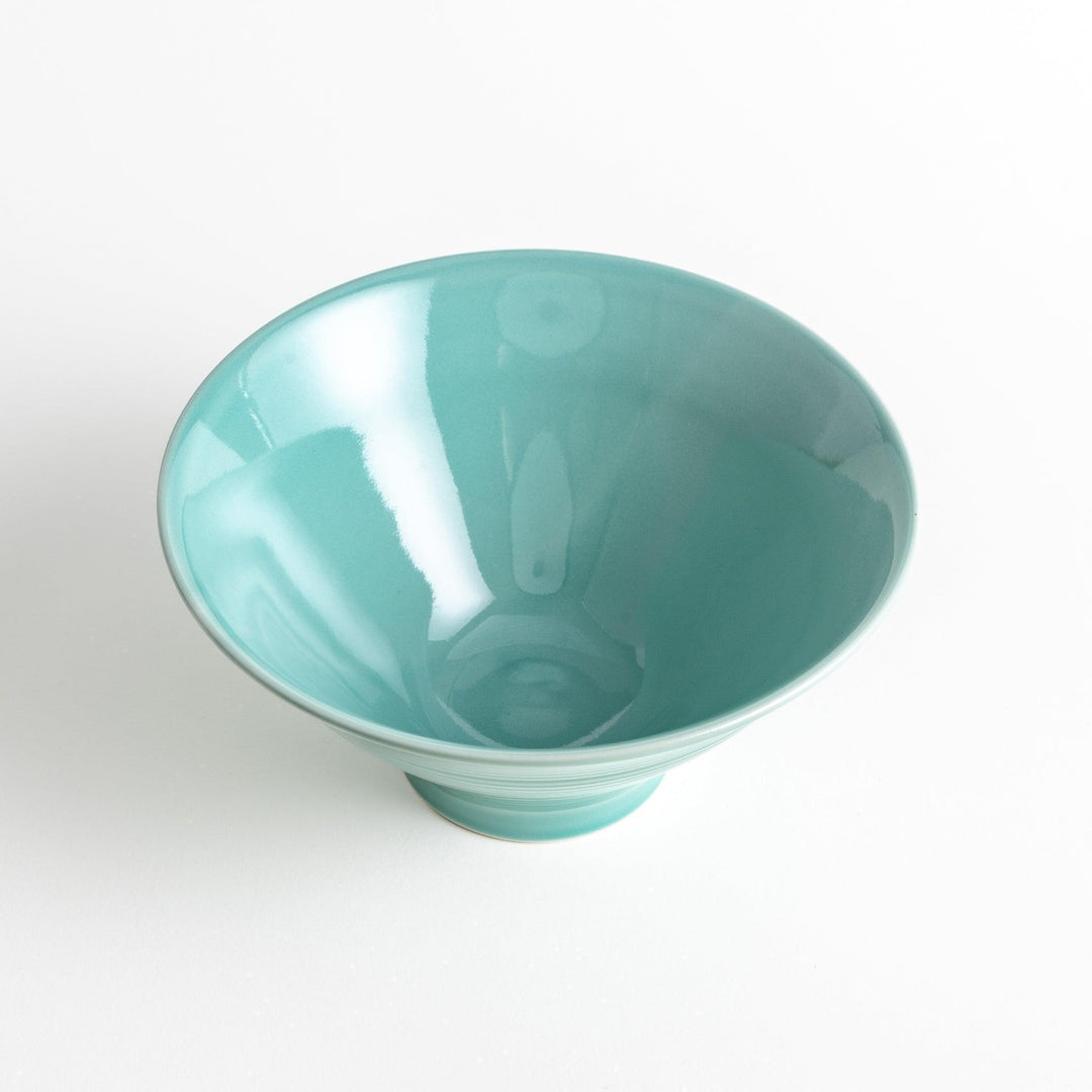 A wide, shallow porcelain bowl with a soft, matte turquoise glaze and subtle horizontal ridges.