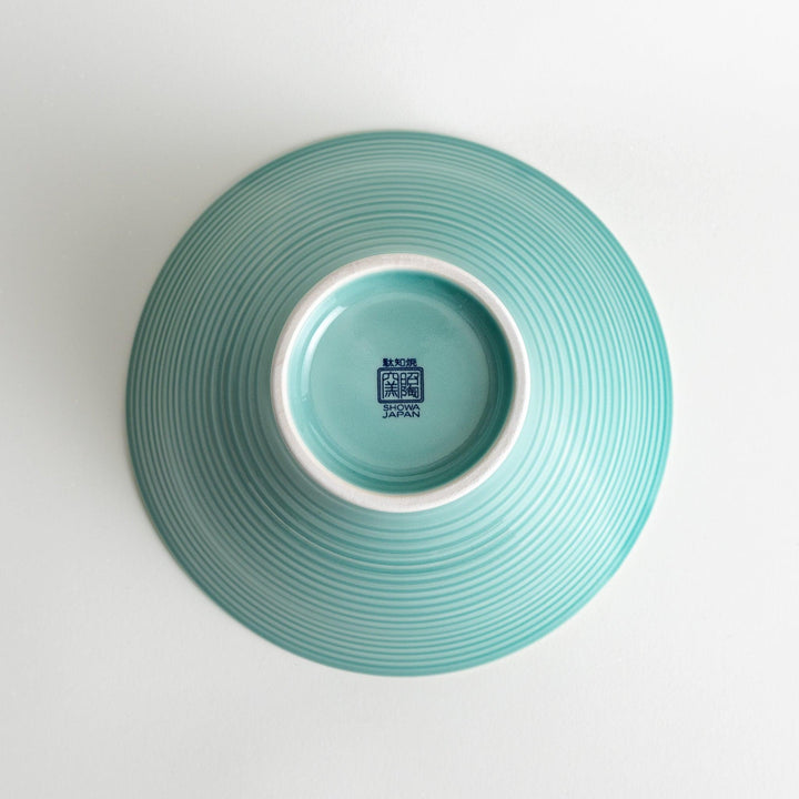 A wide, shallow porcelain bowl with a soft, matte turquoise glaze and subtle horizontal ridges.