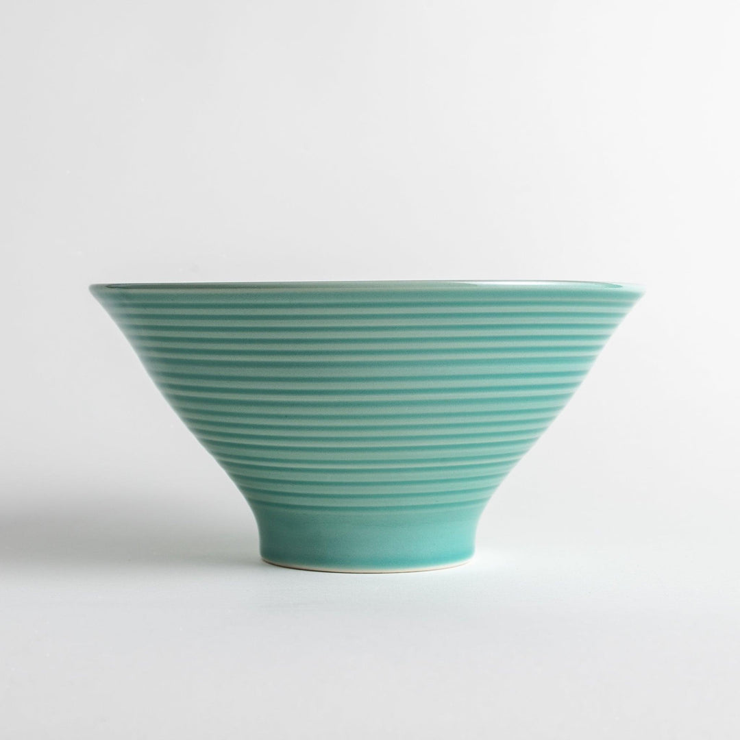 A wide, shallow porcelain bowl with a soft, matte turquoise glaze and subtle horizontal ridges.