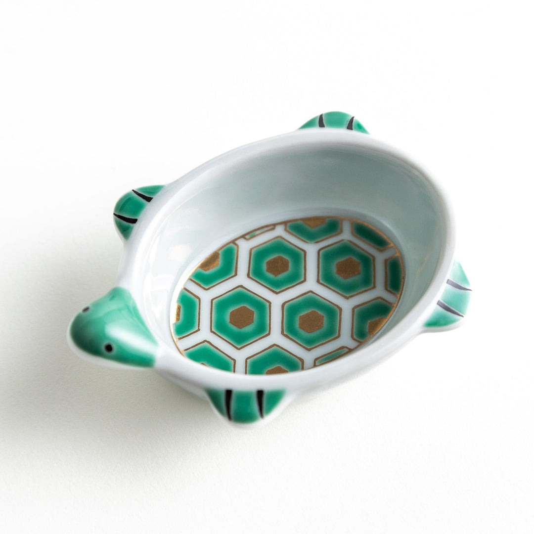 A small, turtle-shaped dish with a green geometric pattern inside.