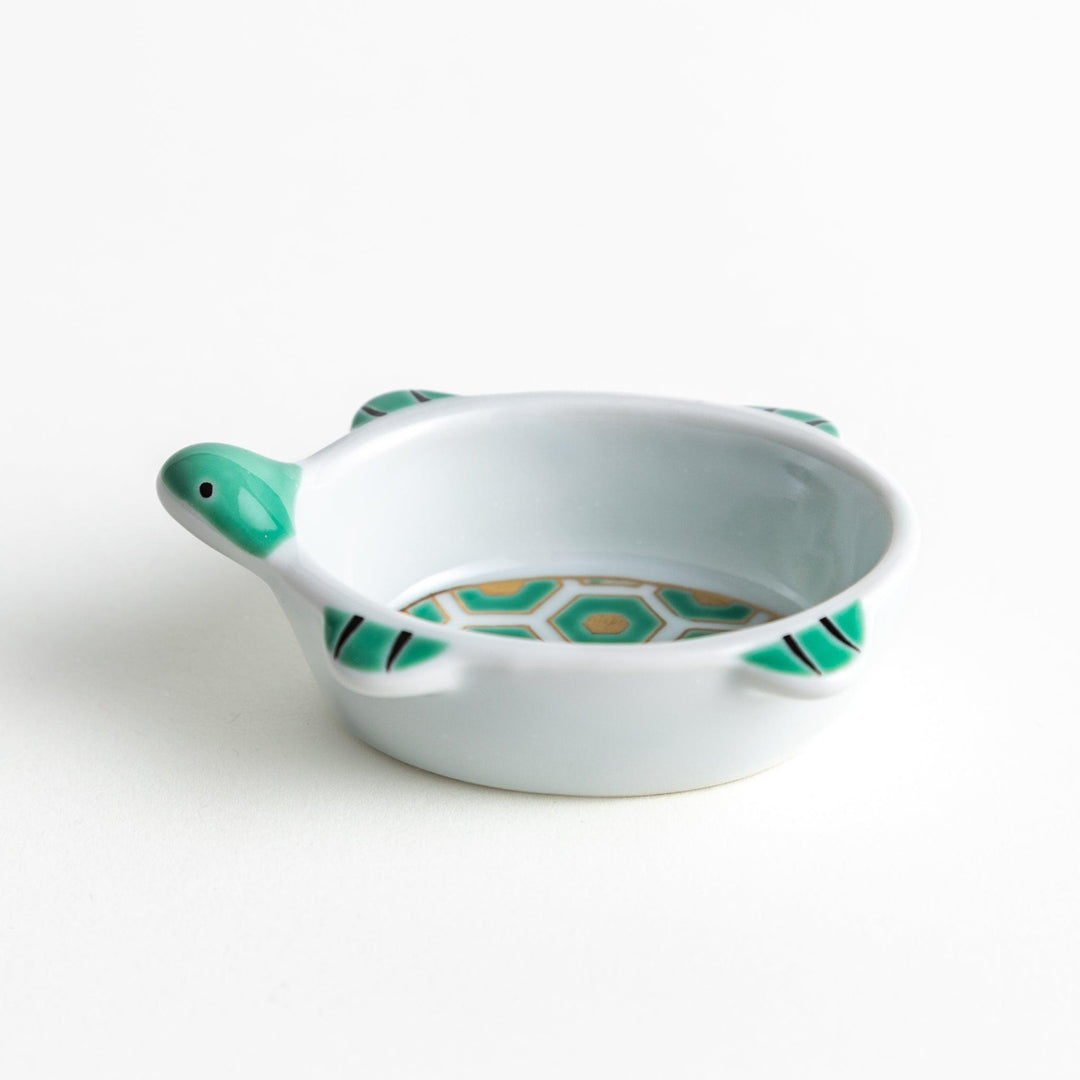 A small, turtle-shaped dish with a green geometric pattern inside.