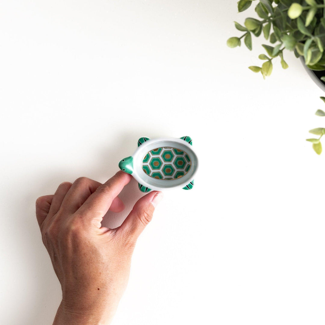 A small, turtle-shaped dish with a green geometric pattern inside.