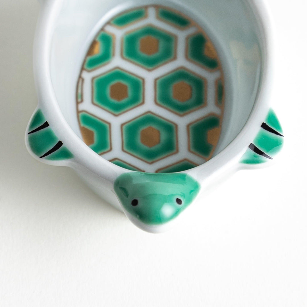 A small, turtle-shaped dish with a green geometric pattern inside.