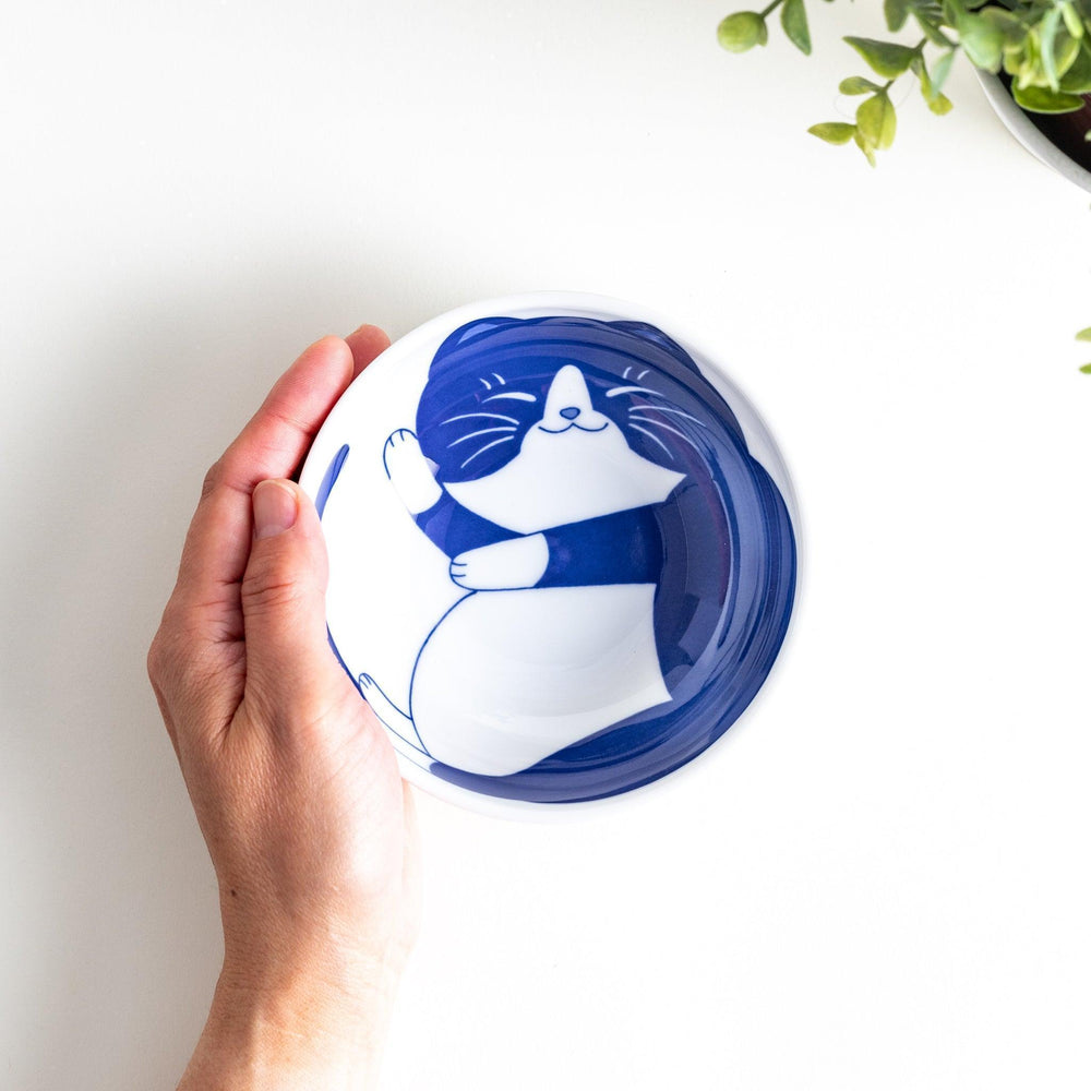 A dessert bowl featuring a black and white cat, peacefully curled up and sleeping.