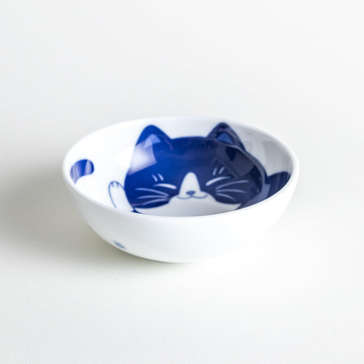 A dessert bowl featuring a black and white cat, peacefully curled up and sleeping.