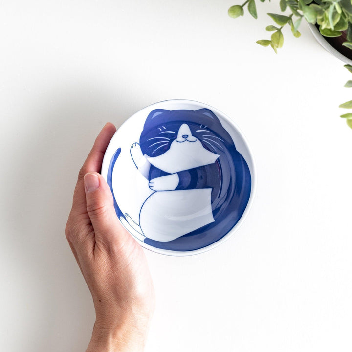 A rice bowl with a curled-up black and white cat design, sleeping peacefully.