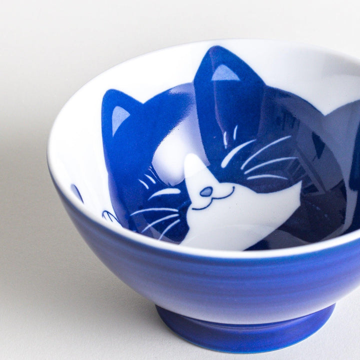 A rice bowl with a curled-up black and white cat design, sleeping peacefully.