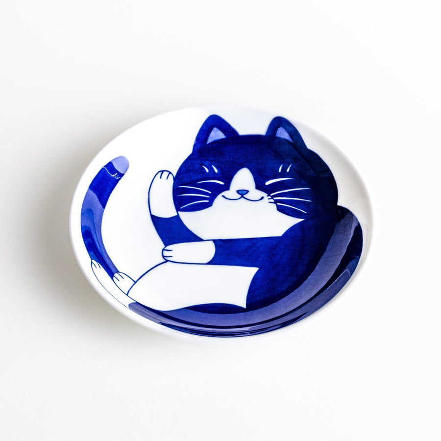 A salad plate featuring a playful black and white cat stretching contentedly.