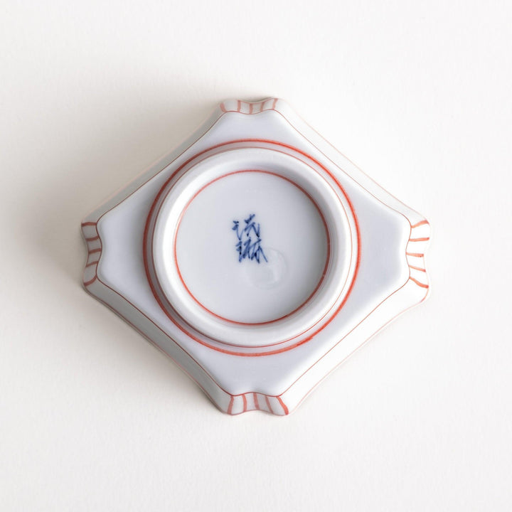 A small square dish with red and blue vertical stripes along the edges, accompanied by a silver spoon.