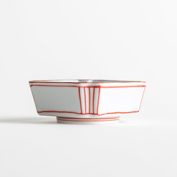 A small square dish with red and blue vertical stripes along the edges, accompanied by a silver spoon.