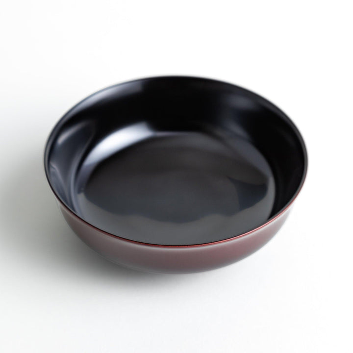 A glossy lacquer bowl with a matching lid, featuring a gold rim around the edge, ideal for serving soups or stews. Available in black or red.