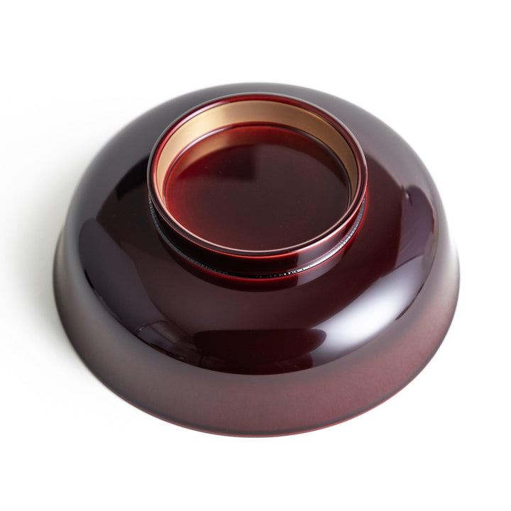 A glossy lacquer bowl with a matching lid, featuring a gold rim around the edge, ideal for serving soups or stews. Available in black or red.