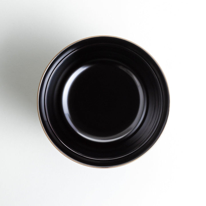 A glossy lacquer bowl with a matching lid, featuring a gold rim around the edge, ideal for serving soups or stews. Available in black or red.