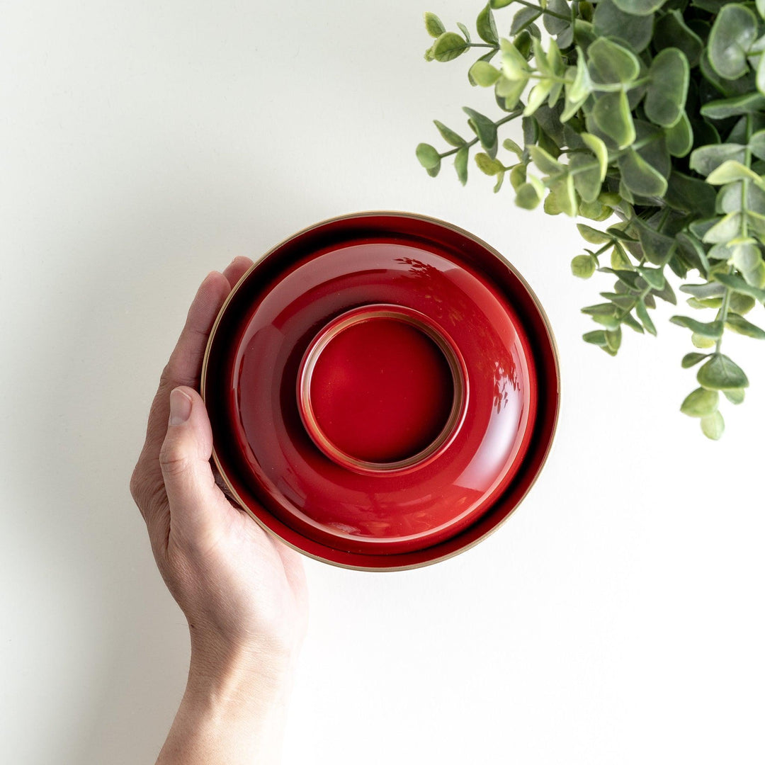 A glossy lacquer bowl with a matching lid, featuring a gold rim around the edge, ideal for serving soups or stews. Available in black or red.