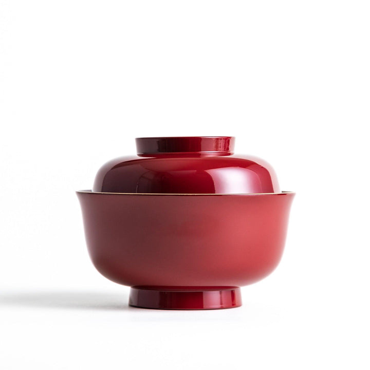 A glossy lacquer bowl with a matching lid, featuring a gold rim around the edge, ideal for serving soups or stews. Available in black or red.