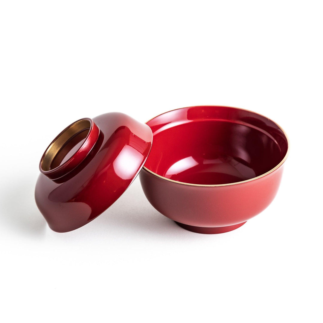 A glossy lacquer bowl with a matching lid, featuring a gold rim around the edge, ideal for serving soups or stews. Available in black or red.