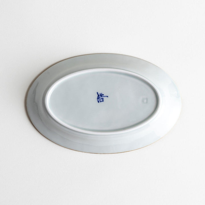 A small oval porcelain plate with subtle blue floral accents on the edges.