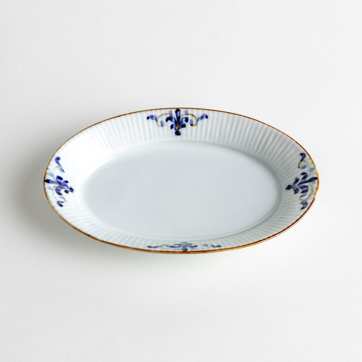 A small oval porcelain plate with subtle blue floral accents on the edges.