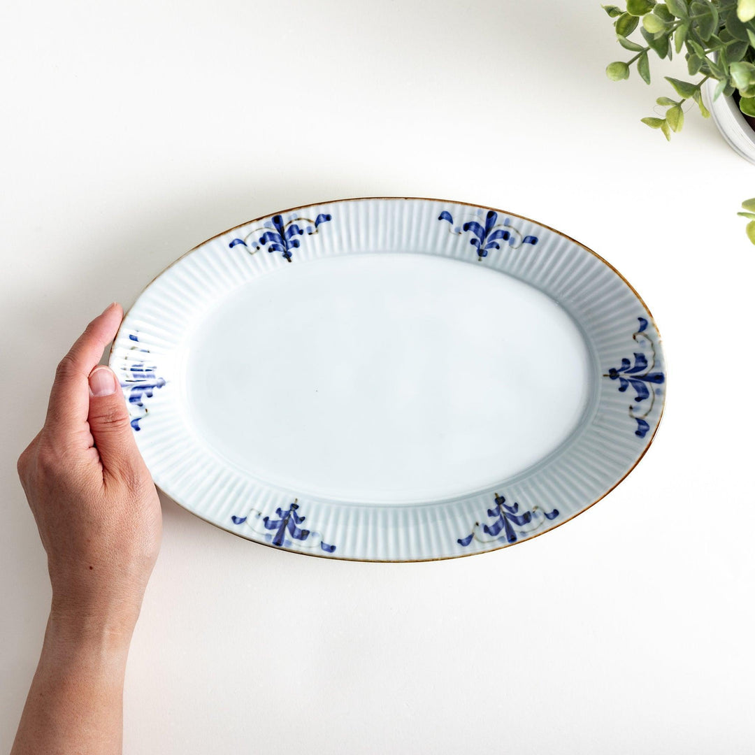 A medium-sized oval porcelain plate adorned with blue floral designs on the edges.