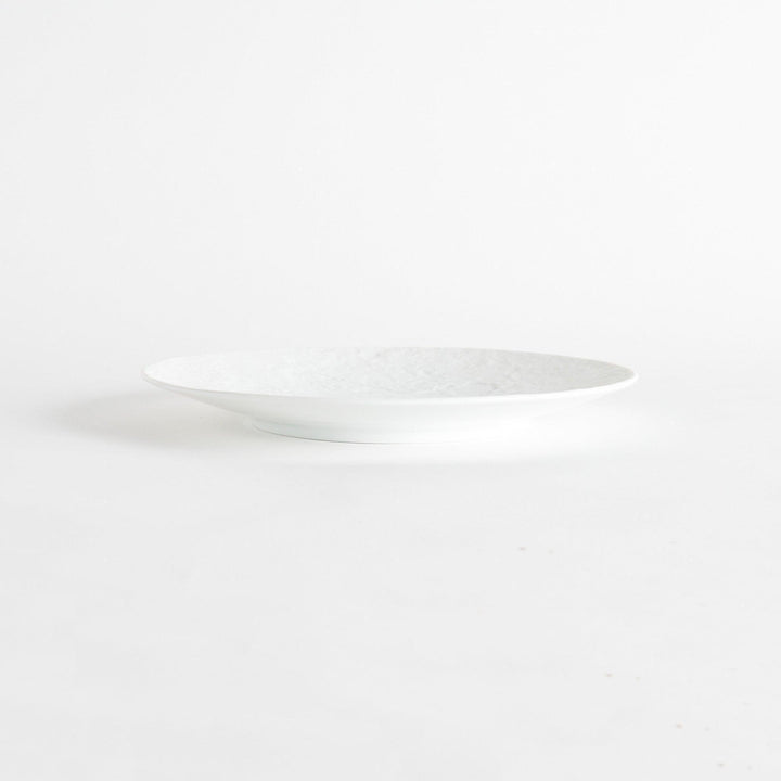 A simple white dinner plate with a subtle texture.