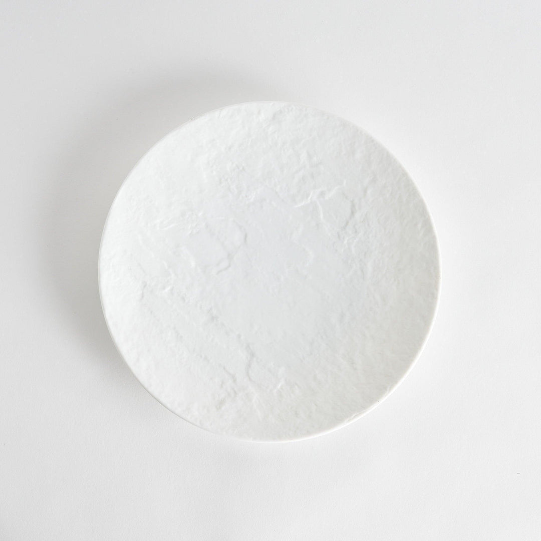 A simple white dinner plate with a subtle texture.