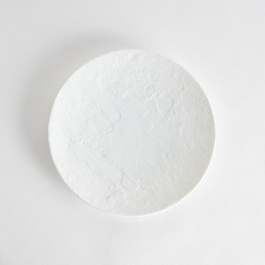 A simple white dinner plate with a subtle texture.