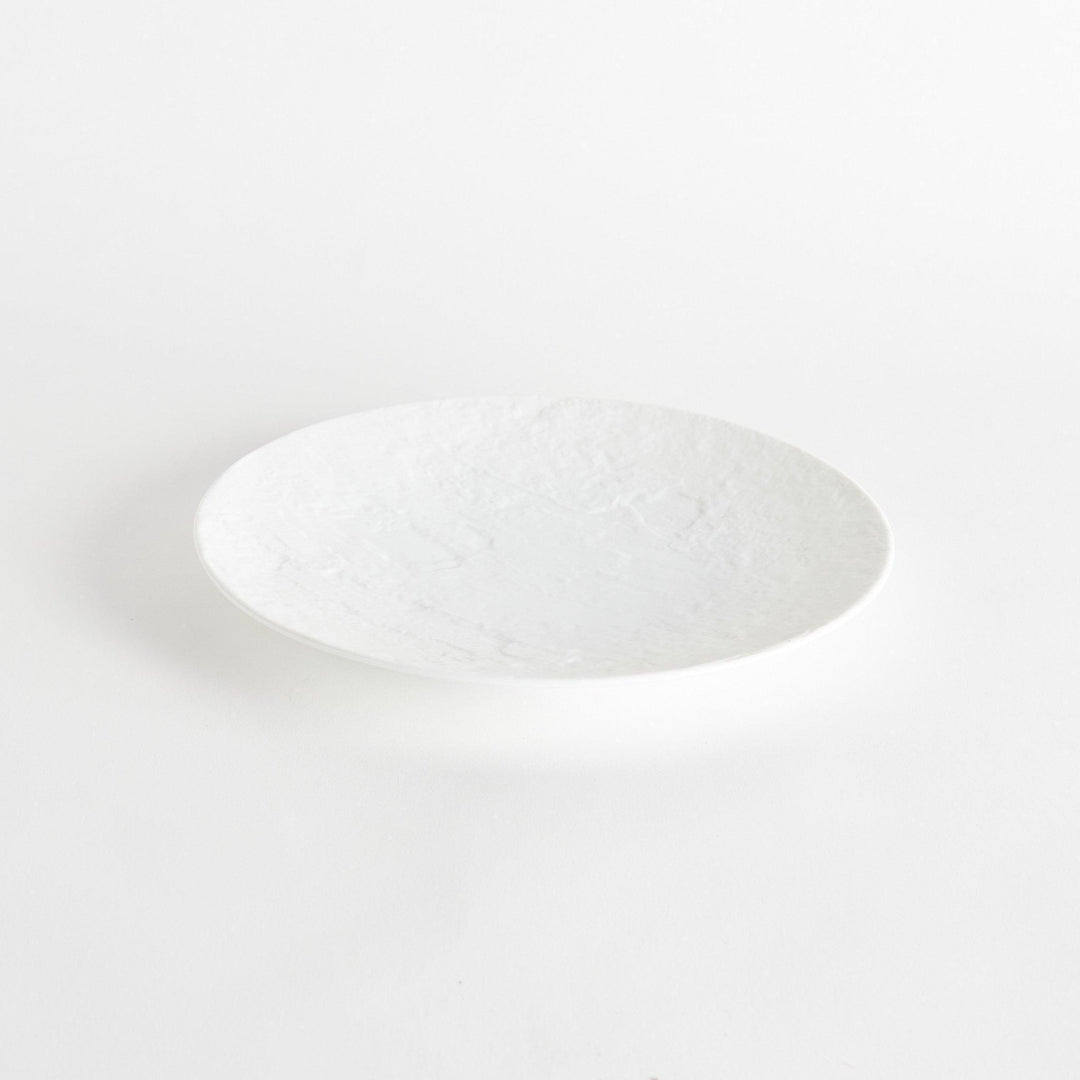 A simple white dinner plate with a subtle texture.