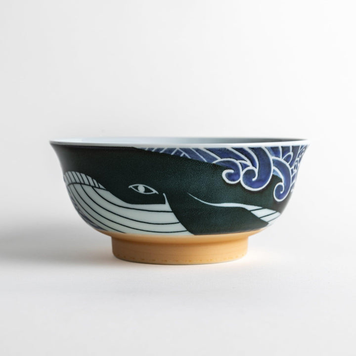 A ramen bowl with a white and blue design, featuring a whale illustration and wave patterns.