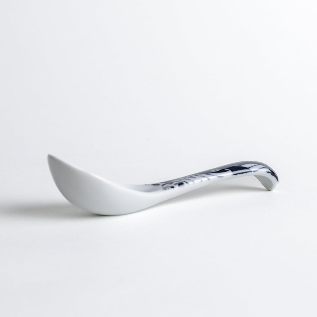 A porcelain soup spoon with a blue wave pattern on the handle.