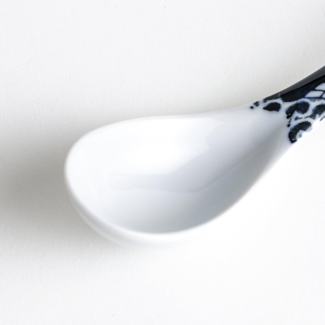 A porcelain soup spoon with a blue wave pattern on the handle.