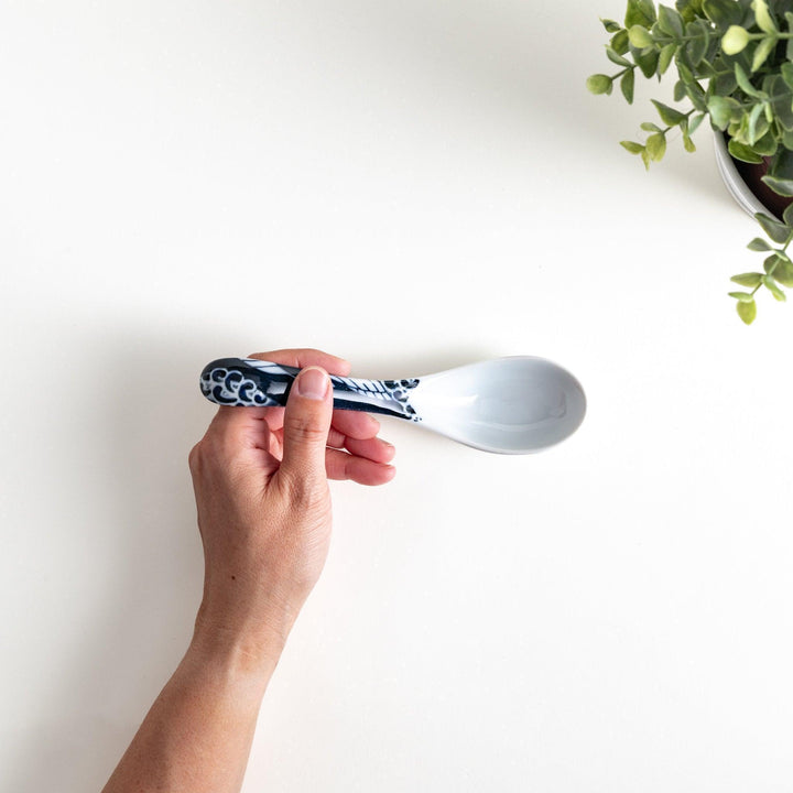 A porcelain soup spoon with a blue wave pattern on the handle.