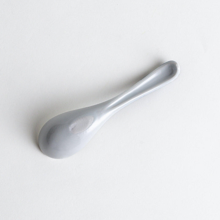 A porcelain soup spoon with a blue wave pattern on the handle.